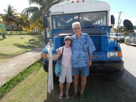 Two expats in front of an old bus that they are hoping to replace for the charity HelpAge Corozal – Best Places In The World To Retire – International Living
